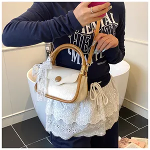 Detail of a retro cream square bag with brown trim and a delicate lace bow charm