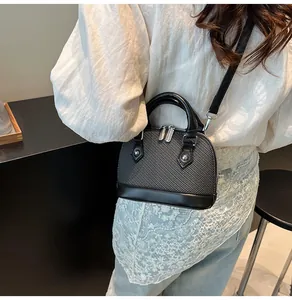 Detail view of mini shell bag in grey woven fabric and black leather on a model