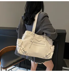 Rear view of cream utility tote bag with metal buckles and multiple functional pockets