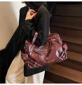 Retro burgundy leather tote bag with rivet details shown on a model on wooden steps