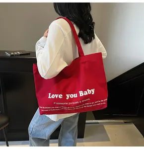 Large red canvas tote bag with Love you Baby print worn by a model in a casual setting