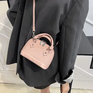 Pink shell handbag with woven texture and crossbody strap worn on gray blazer