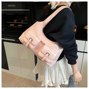 Detail of pink glossy patent leather shoulder bag featuring dual pockets and metal buckles