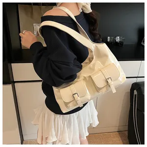 Detail of creamy white patent leather shoulder bag with glossy finish and cargo pockets