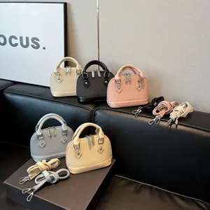 Minimalist shell-shaped crossbody handbag in five soft colors on a leather sofa