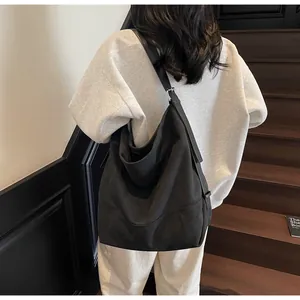 Large black canvas tote bag with adjustable shoulder strap shown from a back view on model