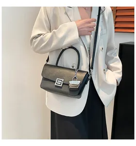 Detail of black vintage shoulder bag with textured leather and square metal buckle