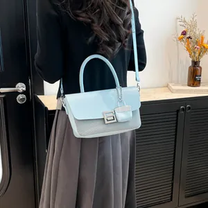 Light blue faux leather shoulder bag with mesh texture and mini charm on a model