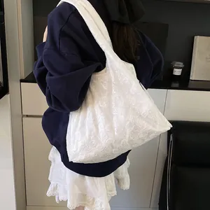 White lace floral tote bag with embroidery details shown on model in a minimalist setting