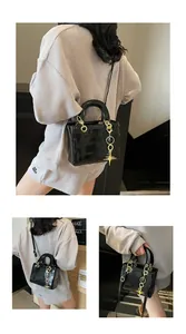 Detail view of black glossy handbag featuring cartoon rabbit embossing and gold star charms