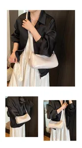 Detail view of cream white glossy underarm bag showing adjustable strap and sleek texture