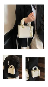 Detailed view of white structured handbag with star embossing and gold hardware