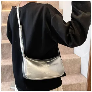 Silver metallic crescent underarm bag worn crossbody over a casual white and black outfit