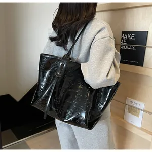 Model draagt een grote zwarte laklederen shopper met reliëf van cartoonpatronen