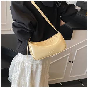 Close-up of a cream pleated underarm bag showing glossy leather texture and zipper detail