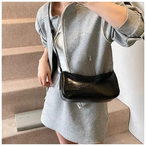 Polished black underarm bag styled with a gray suit on stairs for a modern chic look