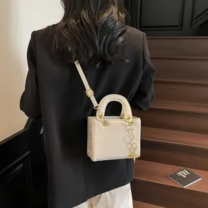 White mini handbag with bear patterns and gold chain crossbody strap on a fashion model