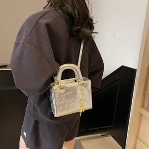 Silver metallic crossbody bag with bear embossing shown on model in studio setting