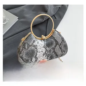 Detail view of snakeskin pattern evening bag with golden ring handle and chain strap