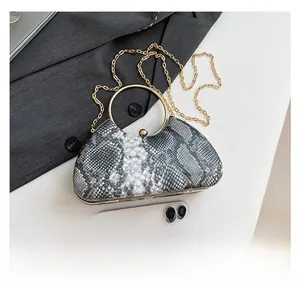 Detail view of snakeskin print evening bag with golden metal handle and size comparison