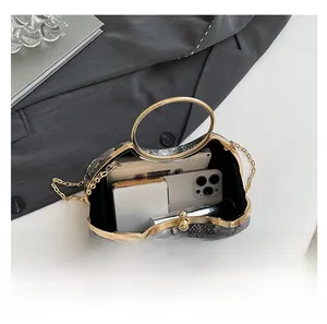 Detail showing snake skin patterned handbag interior capacity with phone and chain strap