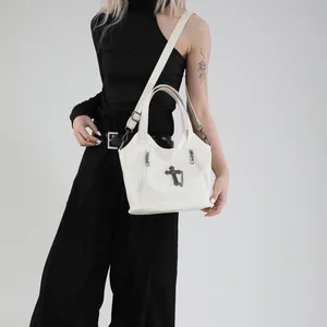 White faux leather crossbody bag with gothic cross and tassel shown on model