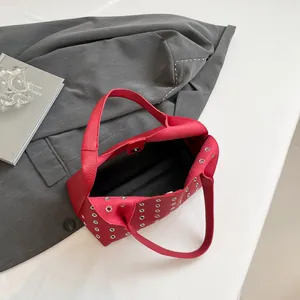 Red lychee leather handbag with silver eyelets shown from above on a minimal background