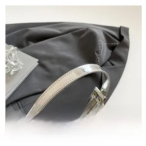 Détail de la bandoulière argentée aux coutures fines et sac transparent avec dorures