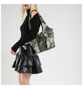 Détail du sac à bandoulière camouflage avec œillets argentés et poches sur un modèle