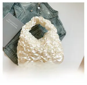 Detail of white pleated satin handbag with elegant silk texture and soft cloud ruffles