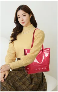On-body view of red glossy patent leather tote bag with white TOTE BAG printing