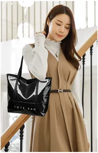 Close-up of a glossy black tote bag with white text print carried by a model