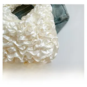 Detailed view of white pleated fabric texture with satin gloss and ruffled layers