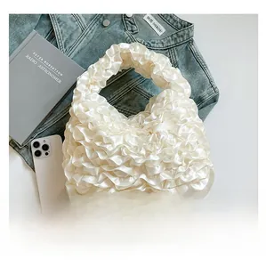 Detailed close-up of white ruffled satin handbag with layered pleats texture