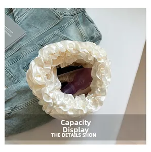Detail view of white satin ruffle handbag capacity with mobile phone and bottle inside