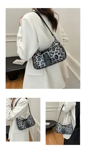 Macro detail of leopard print shoulder bag featuring silver rivets and large buckle strap