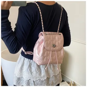Vista dettagliata di un mini zaino rosa trapuntato con spallacci a catena su modella
