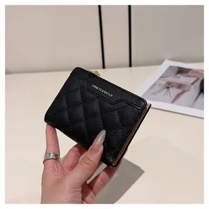 Close-up of black quilted leather wallet showing metal logo and pink lining texture