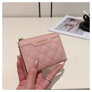 Detailed macro shot of pink quilted leather wallet with gold zipper and metal logo