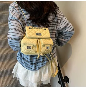 Mini sac à dos matelassé jaune avec fermoirs rotatifs argentés et bretelles en chaîne