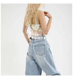 Détail d'un sac d'épaule transparent en PVC avec bordure dorée porté par un mannequin