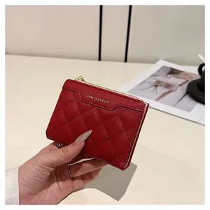 Detail of red quilted wallet with gold zipper closure and textured leather surface