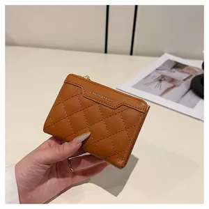 Close-up of quilted tan leather wallet featuring gold logo and smooth zipper detail
