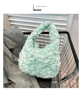 Detail of green ruffled handbag with satin texture placed in a metal shopping cart