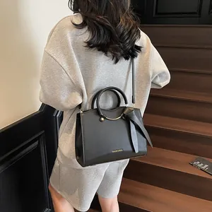 Sac cabas chic en cuir PU noir avec lettres dorées et nœud dans un cadre urbain