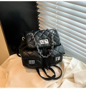 Détail d'un mini sac à dos matelassé noir avec chaînes en métal argenté et fermoirs rotatifs
