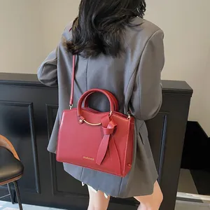Sac fourre-tout rouge mat avec poignées métalliques et détails de ruban élégant