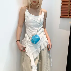 Blue spherical shell bag with baseball stitching details and silver chain strap on a model