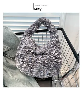 Detail of gray ruffled handbag featuring silk-like fabric pleats and layered design