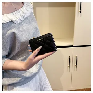 Close-up of quilted black short wallet with gold zipper held in a lifestyle setting
